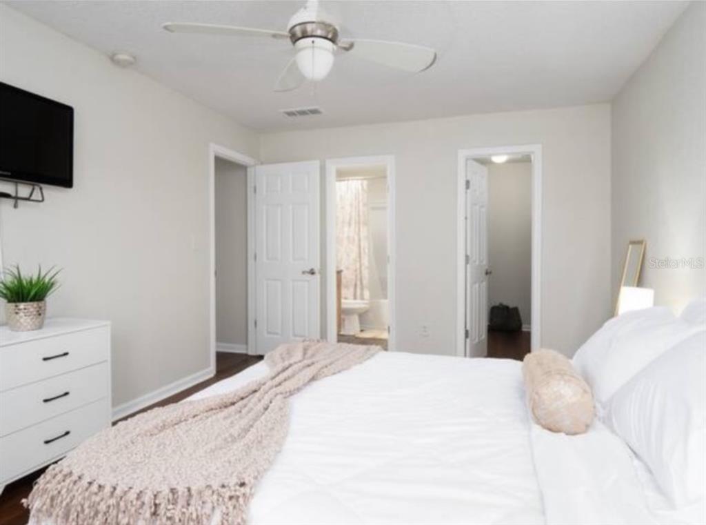 A bedroom features a white bed, a dresser, a ceiling fan, and three doorways — 1810 NW 23RD BOULEVARD UNIT 178, GAINESVILLE, FL