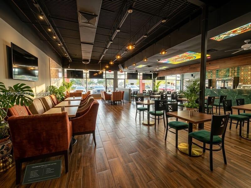 A restaurant interior features wood-look tile floors, velvet chairs, pendant lighting, and a black ceiling — N State Road 7, Tamarac FL 33319, TAMARAC, FL