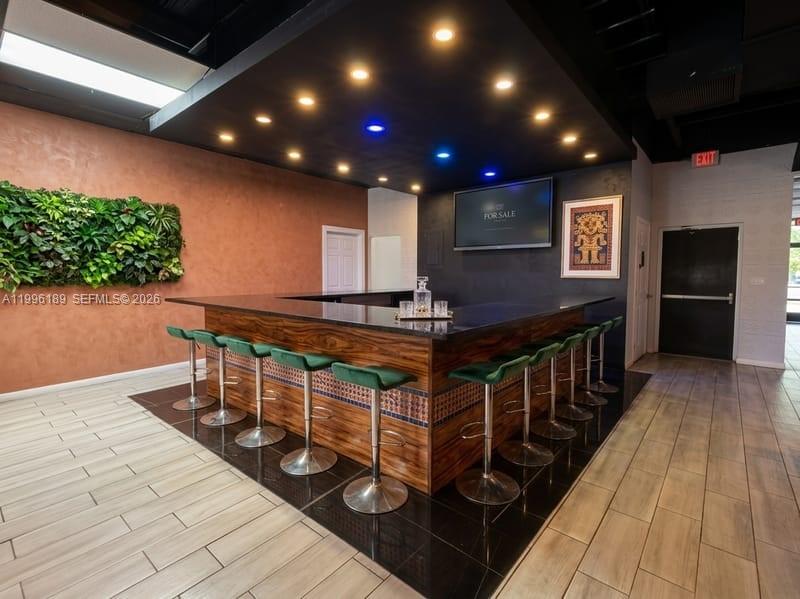 A bar area features a wooden counter, green stools, and a black ceiling with recessed lighting — N State Road 7, Tamarac FL 33319, TAMARAC, FL
