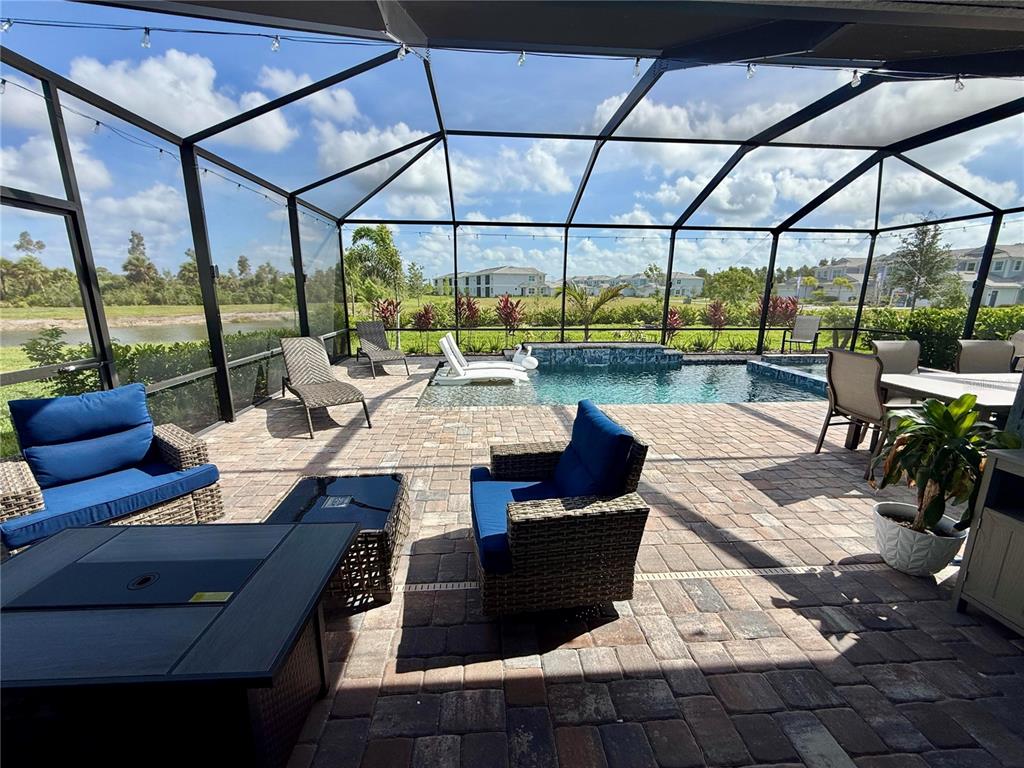A screened-in patio features a swimming pool, outdoor furniture, and a view of a pond — 10852 SUN DROP STREET, VENICE, FL