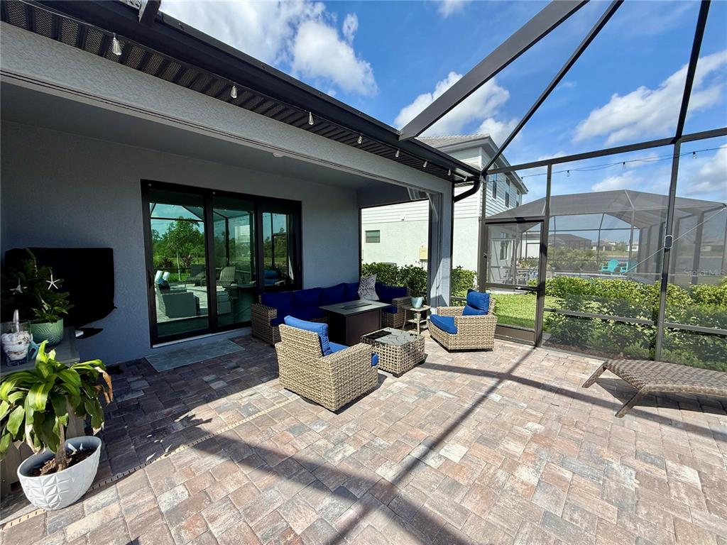 A covered patio with brick pavers, outdoor furniture, and a screened-in enclosure — 10852 SUN DROP STREET, VENICE, FL