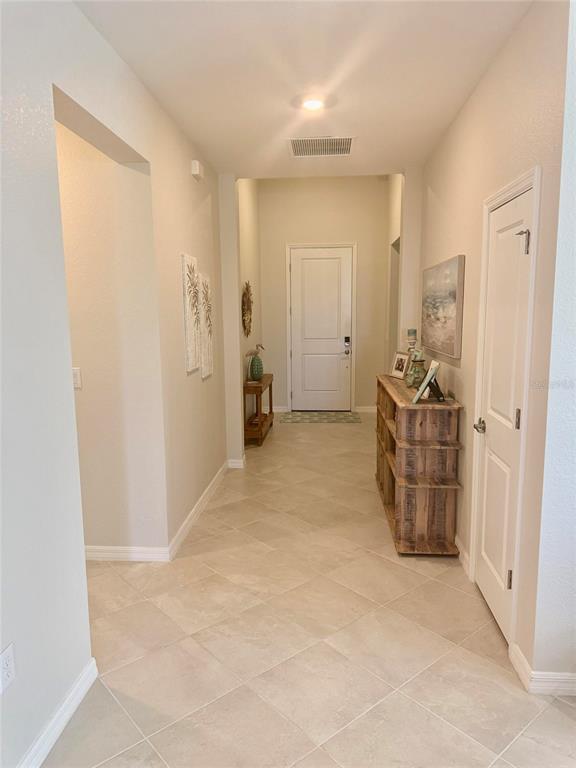 A tiled entryway features a wooden console table, wall art, and a white front door — 10852 SUN DROP STREET, VENICE, FL