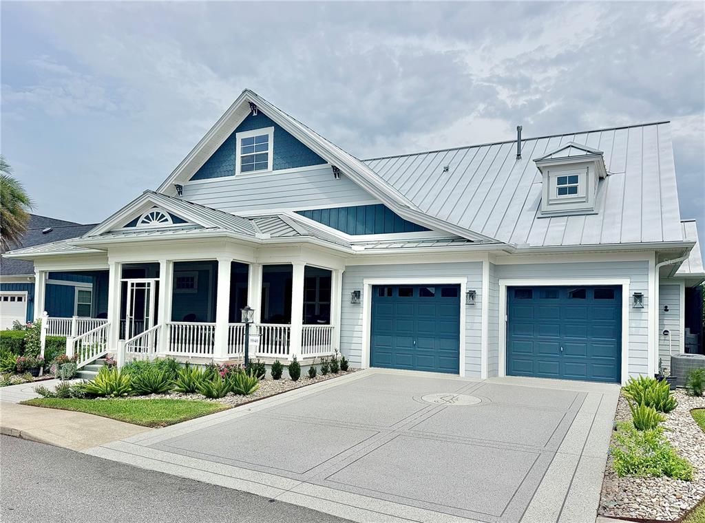 A light blue house with a metal roof, two garage doors, and a front porch — 1040 COTTAGE DRIVE, THE VILLAGES, FL