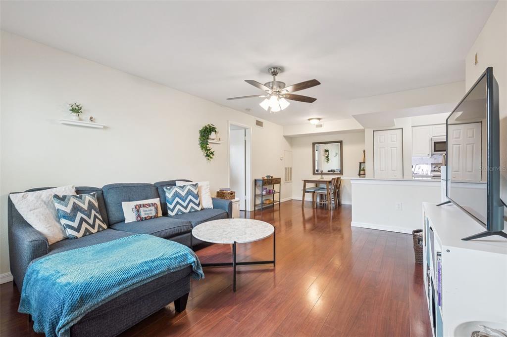 A living room with a grey sectional sofa, coffee table, and open kitchen in the background — 3032 PARKWAY BOULEVARD UNIT 305, KISSIMMEE, FL