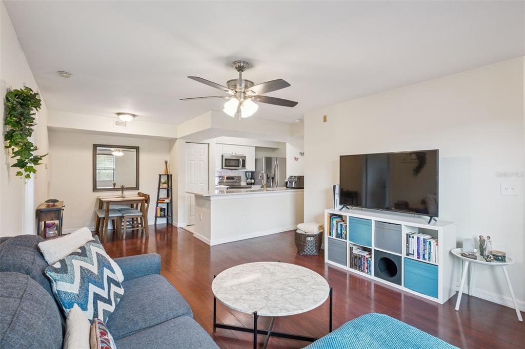 A living room with hardwood floors, a ceiling fan, and an open kitchen area — 3032 PARKWAY BOULEVARD UNIT 305, KISSIMMEE, FL