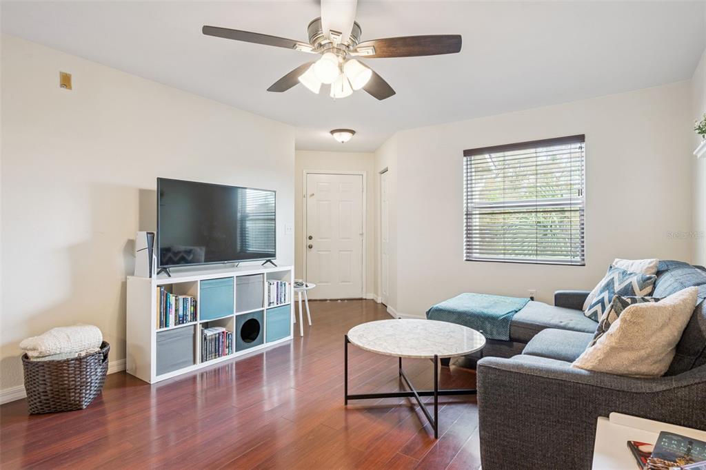 A living room features dark wood floors, a ceiling fan, a television, and a sectional sofa — 3032 PARKWAY BOULEVARD UNIT 305, KISSIMMEE, FL