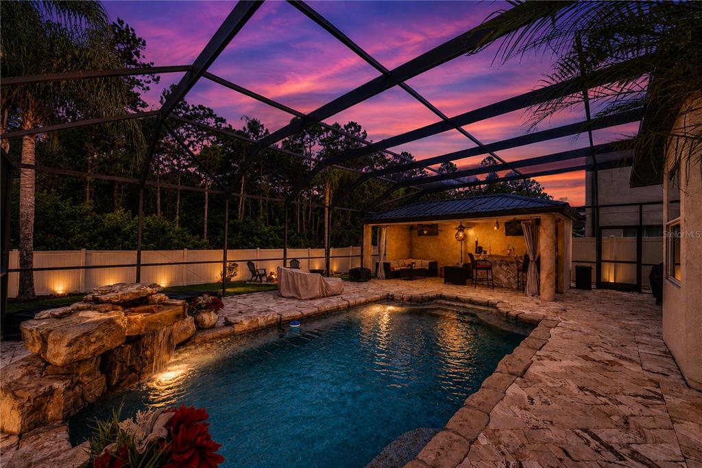 A screened-in patio features a stone-accented swimming pool with a waterfall and a covered bar — 13115 ROYAL GEORGE AVENUE, ODESSA, FL