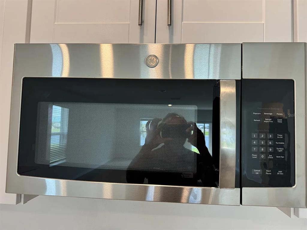 A stainless steel GE over-the-range microwave is mounted beneath white kitchen cabinets — 8513 8513 BLUE WAVE LN, FL, PARRISH, FL