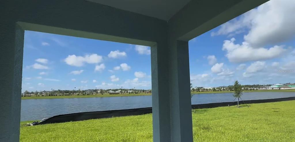 A view of a lake and grassy yard from a covered patio — 8513 8513 BLUE WAVE LN, FL, PARRISH, FL
