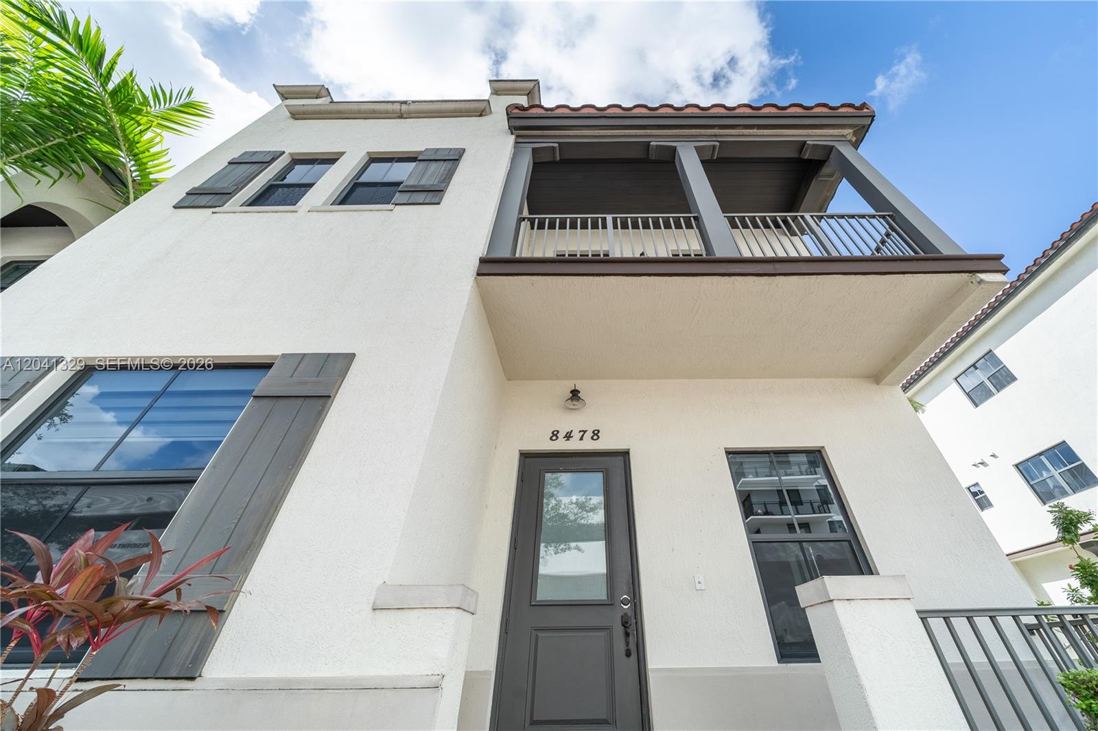 A low-angle view shows the exterior of a white stucco townhouse with a balcony — 8478 NW 52nd St, Doral FL 33166, DORAL, FL