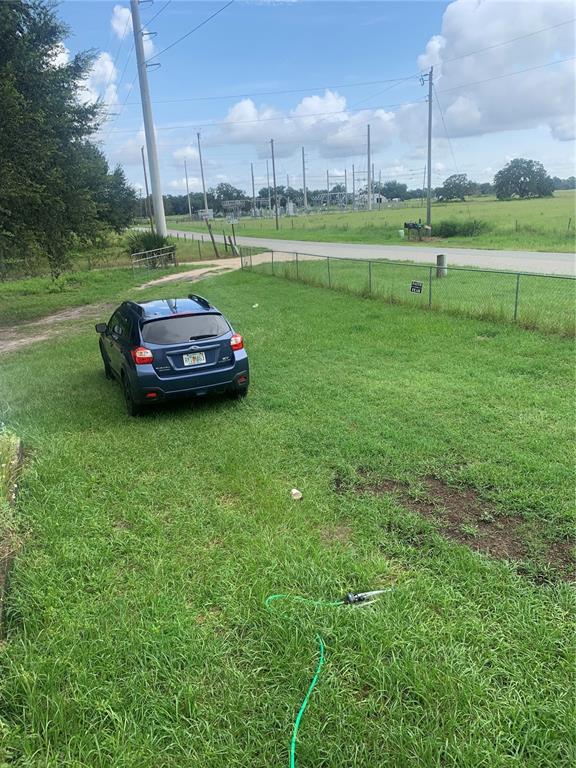 A blue SUV is parked on a grassy lawn next to a chain-link fence — 1218 CR 416N, LAKE PANASOFFKEE, FL