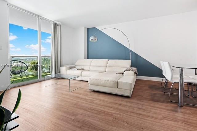 A living room features a white sectional sofa, a glass coffee table, and a blue accent wall — 1800 N Bayshore Dr # 1604, Miami FL 33132, MIAMI, FL