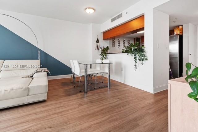 A living and dining area features white walls, wood flooring, and a glass-topped dining table — 1800 N Bayshore Dr # 1604, Miami FL 33132, MIAMI, FL