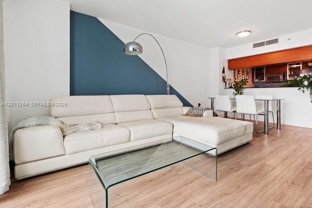 A living room features a white sectional sofa, a glass coffee table, and blue accent wall — 1800 N Bayshore Dr # 1604, Miami FL 33132, MIAMI, FL