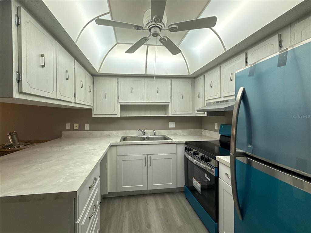 A kitchen features white cabinets, light countertops, a ceiling fan, and a blue refrigerator — 22333 EDGEWATER DRIVE UNIT B1, PORT CHARLOTTE, FL