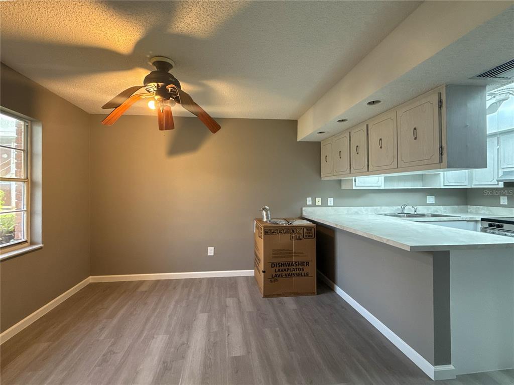 A kitchen and dining area with gray walls, wood-look flooring, and a ceiling fan — 22333 EDGEWATER DRIVE UNIT B1, PORT CHARLOTTE, FL