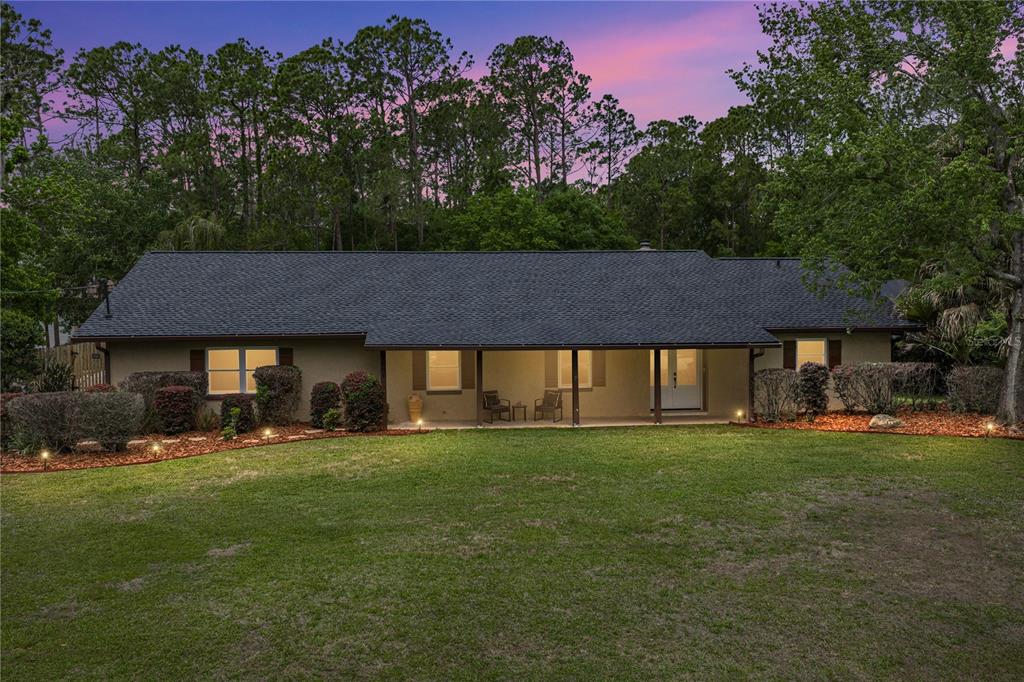 A single-story house with a dark shingled roof and a covered porch at dusk — 7601 THUNDERHEAD STREET, WESLEY CHAPEL, FL