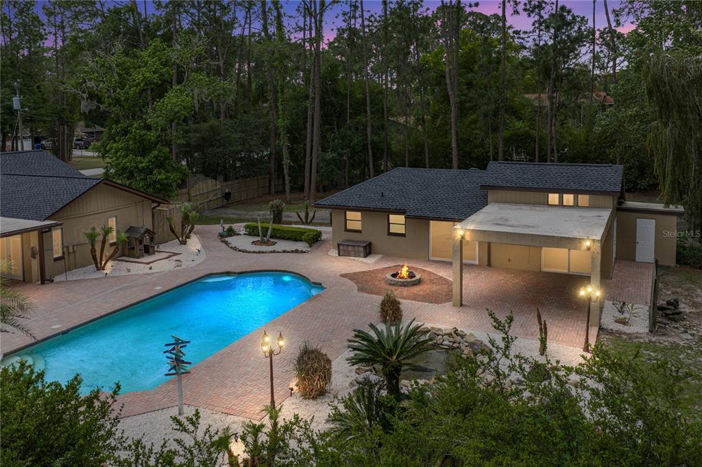 An aerial view of a backyard featuring a swimming pool, brick patio, and fire pit — 7601 THUNDERHEAD STREET, WESLEY CHAPEL, FL