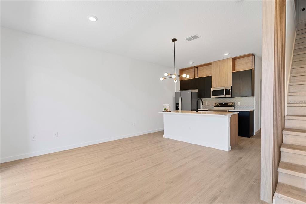 A modern kitchen with black cabinets and light wood accents overlooks an open living area — 3261 TRANQUIL TRAIL, KISSIMMEE, FL