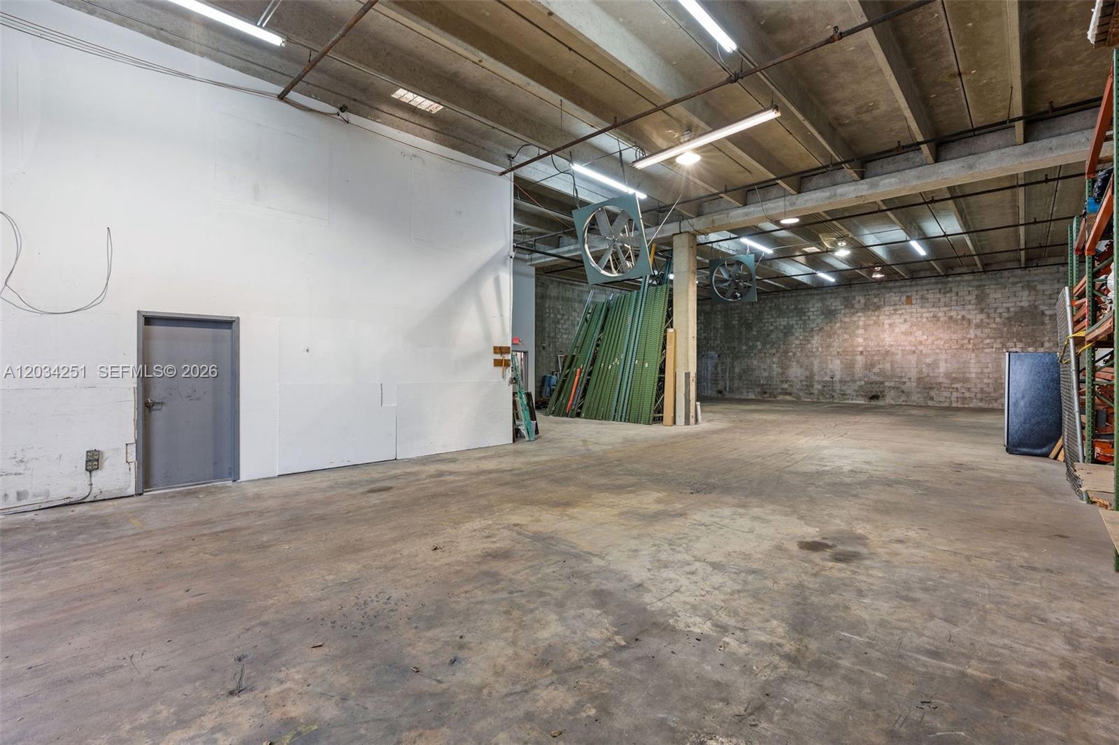 An industrial warehouse space features concrete floors, exposed ceiling beams, and large wall-mounted fans — 3000 NW 79th Ave # 3000, Doral FL 33122, DORAL, FL