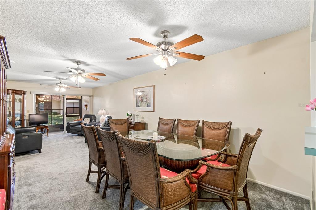 A dining area with a glass-topped wicker table and chairs sits beneath a ceiling fan — 11340 CARRIAGE HILL DRIVE UNIT 4, PORT RICHEY, FL