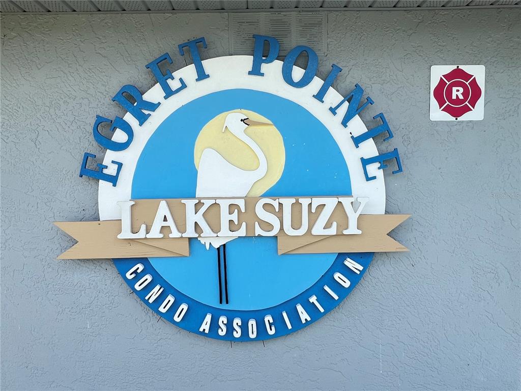 A circular sign for Egret Pointe Lake Suzy Condo Association is mounted on a wall — 12274 SW EGRET CIRCLE UNIT 3703, LAKE SUZY, FL
