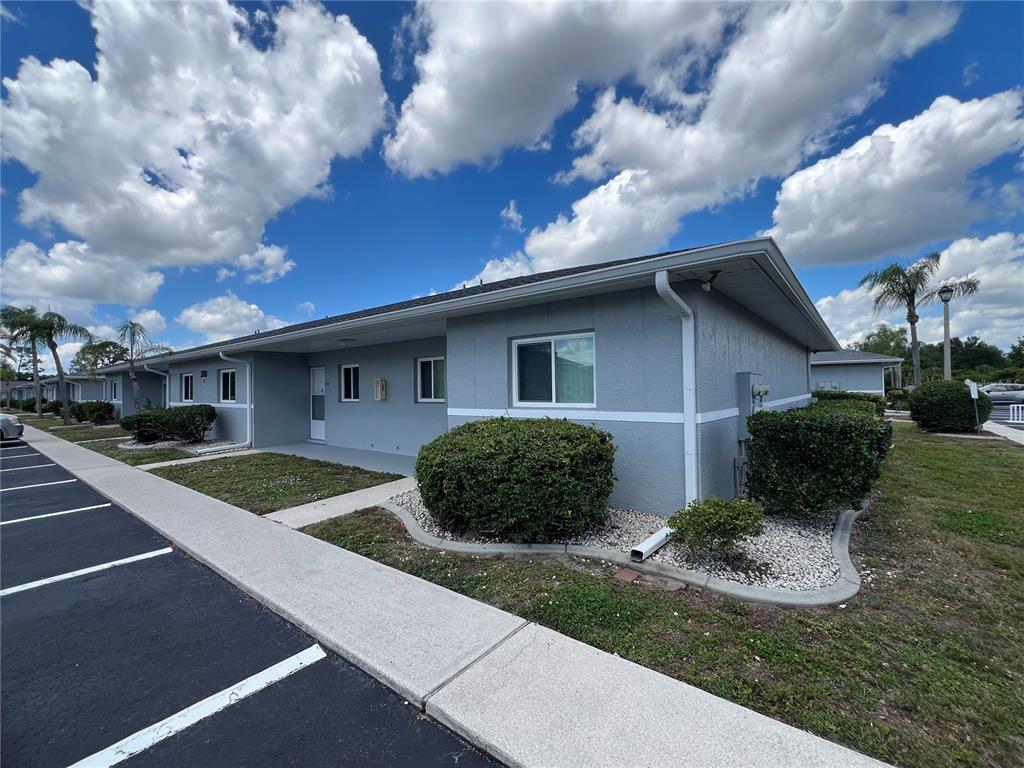 A single-story gray apartment building with a sidewalk and parking lot in front — 12274 SW EGRET CIRCLE UNIT 3703, LAKE SUZY, FL