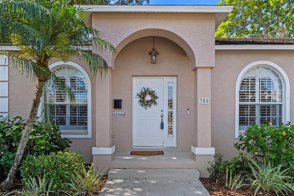 The exterior of a beige house features an arched entryway, a white door, and windows — 350 47TH AVENUE N, ST PETERSBURG, FL