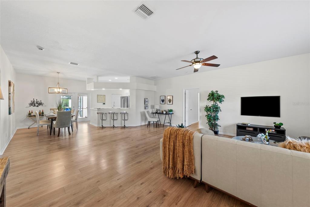 An open-concept living and dining area features light wood flooring and a kitchen breakfast bar — 350 47TH AVENUE N, ST PETERSBURG, FL