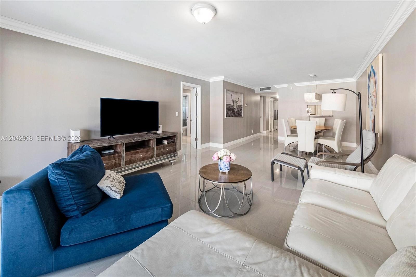 A living room features a blue sofa, white sectional, television console, and dining area — 2097 S Ocean Dr # 411, Hallandale Beach FL 33009, HALLANDALE BEACH, FL