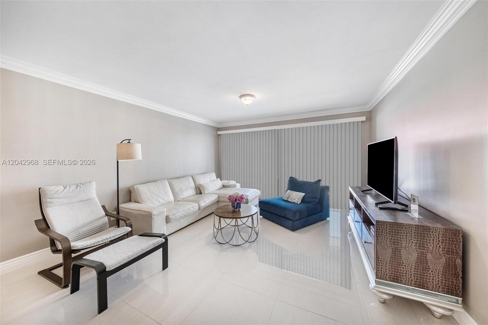 A living room features a white sectional sofa, a blue chair, and a television console — 2097 S Ocean Dr # 411, Hallandale Beach FL 33009, HALLANDALE BEACH, FL