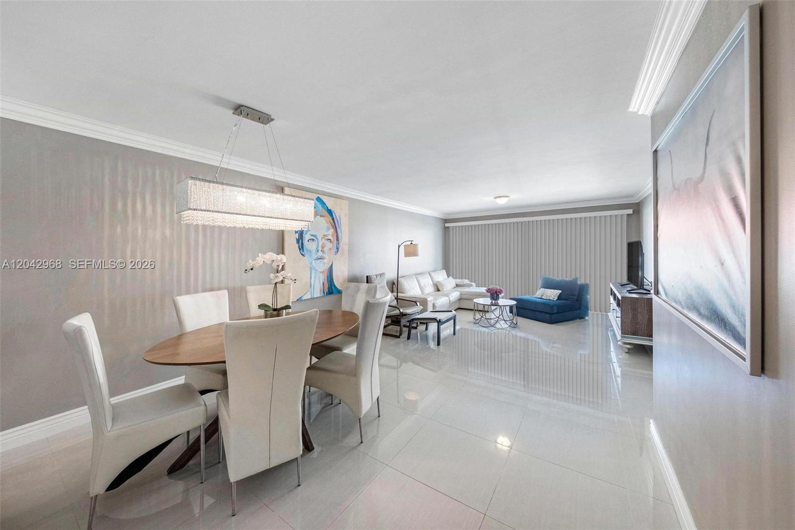A dining area and living room feature white tile floors, a crystal chandelier, and artwork — 2097 S Ocean Dr # 411, Hallandale Beach FL 33009, HALLANDALE BEACH, FL