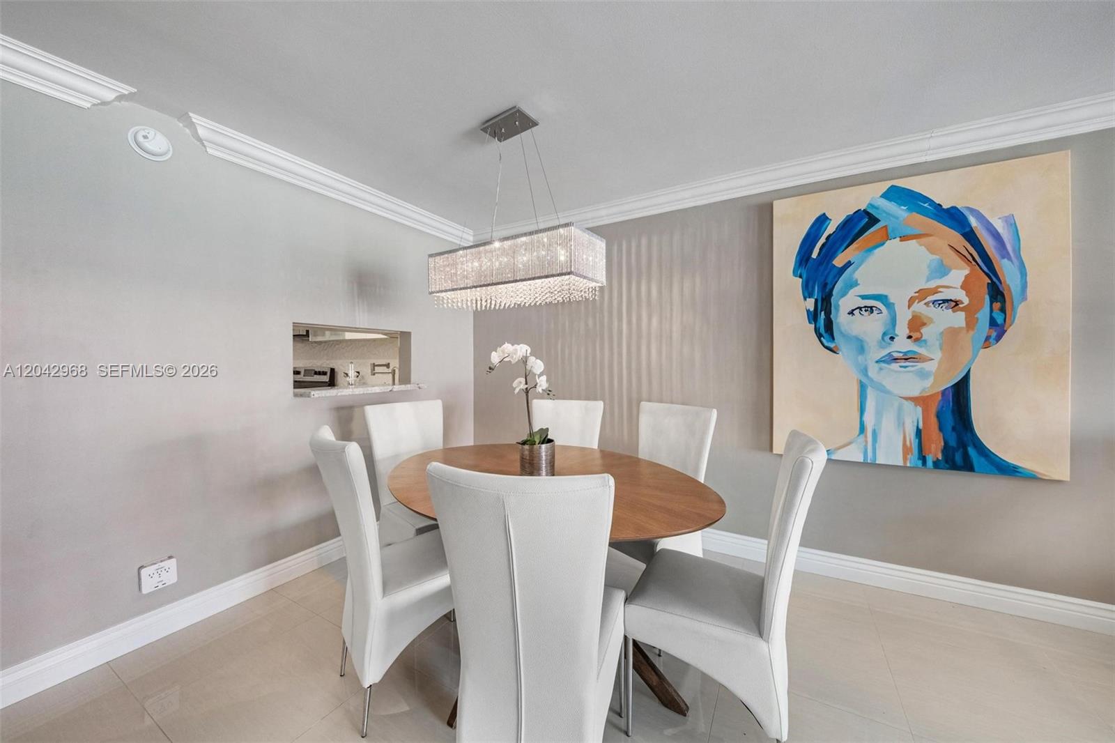 A dining room features a wooden oval table, white chairs, and a large abstract painting — 2097 S Ocean Dr # 411, Hallandale Beach FL 33009, HALLANDALE BEACH, FL
