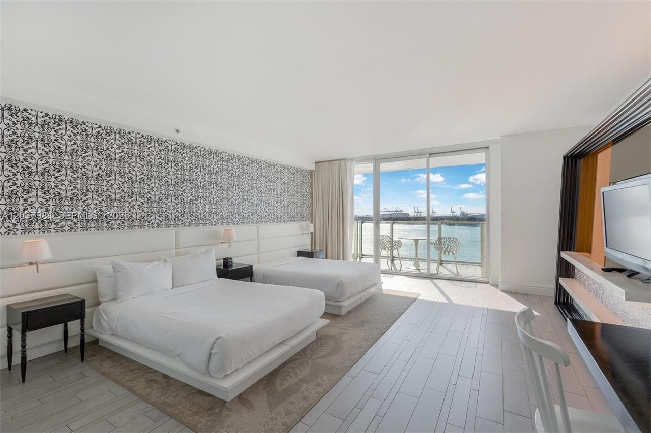 A hotel room with two beds, patterned wallpaper, and a balcony overlooking the water — 1100 West Ave # 1012, Miami Beach FL 33139, MIAMI BEACH, FL