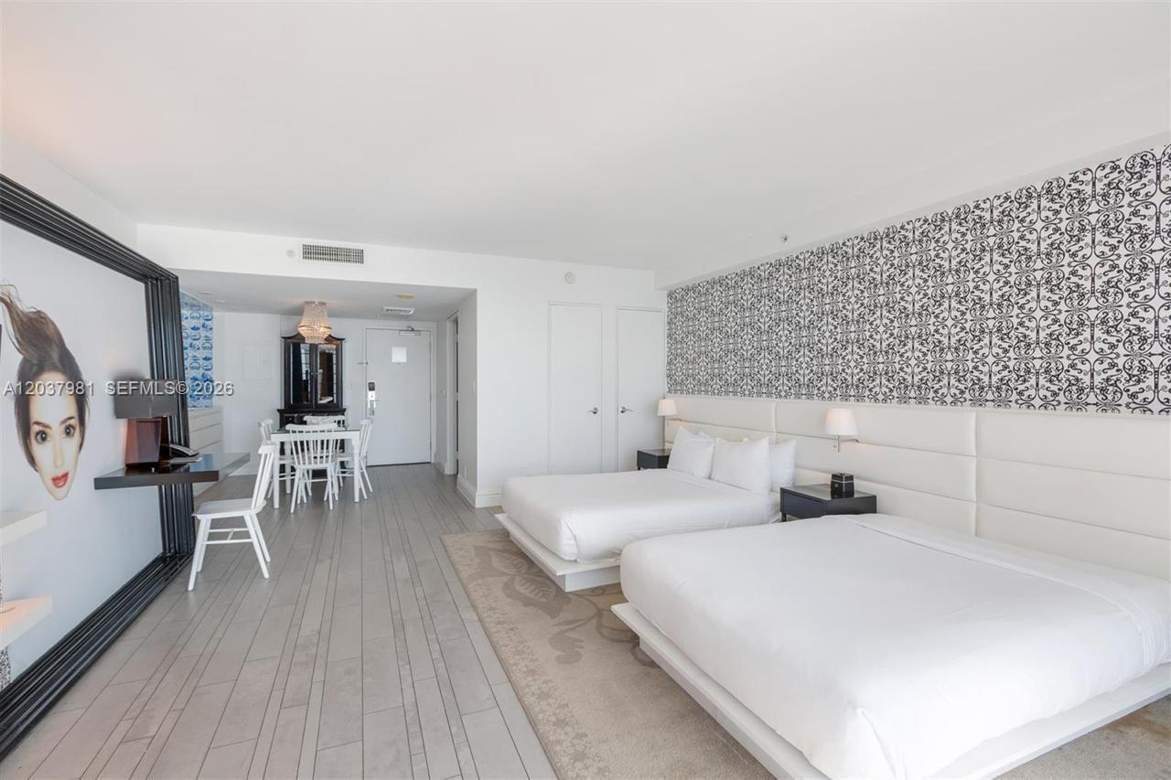 A hotel room features two beds, a dining area, and a large wall-mounted portrait — 1100 West Ave # 1012, Miami Beach FL 33139, MIAMI BEACH, FL
