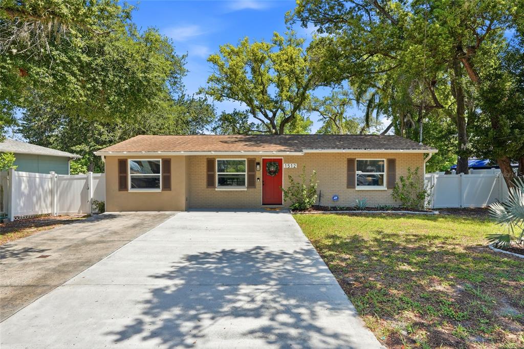 A single-story brick house with a red front door and a concrete driveway — 1512 E HANNA AVENUE, TAMPA, FL