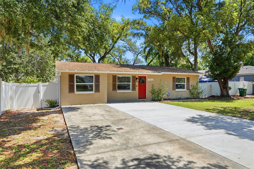 A single-story brick house with a red front door and a concrete driveway — 1512 E HANNA AVENUE, TAMPA, FL