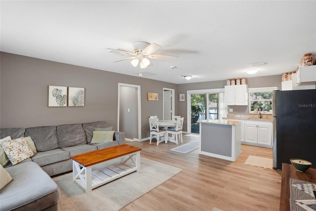 An open-concept living room and kitchen featuring gray walls, wood-look flooring, and white cabinetry — 1512 E HANNA AVENUE, TAMPA, FL