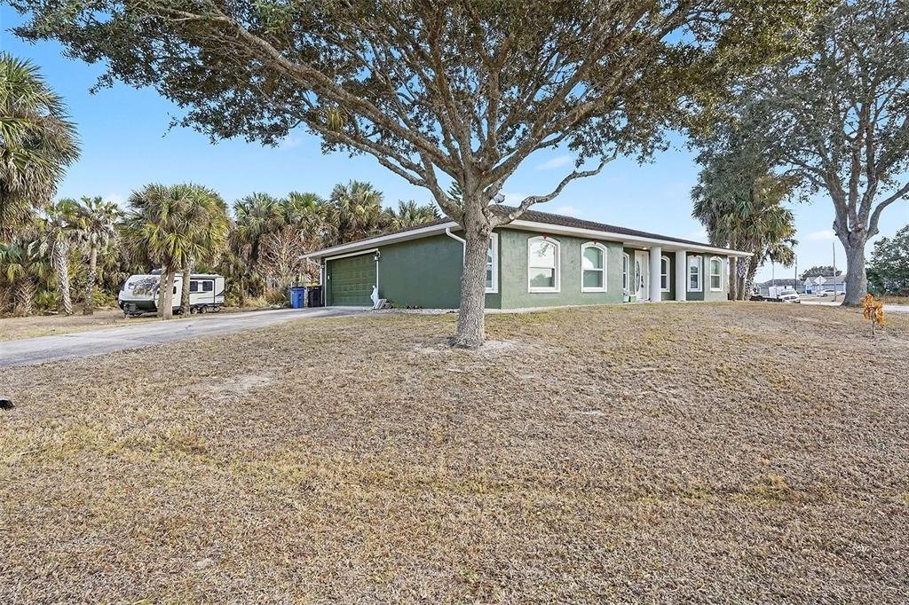 A single-story green house with a two-car garage sits on a large, grassy lot — 598 GANTRY STREET SW, PALM BAY, FL