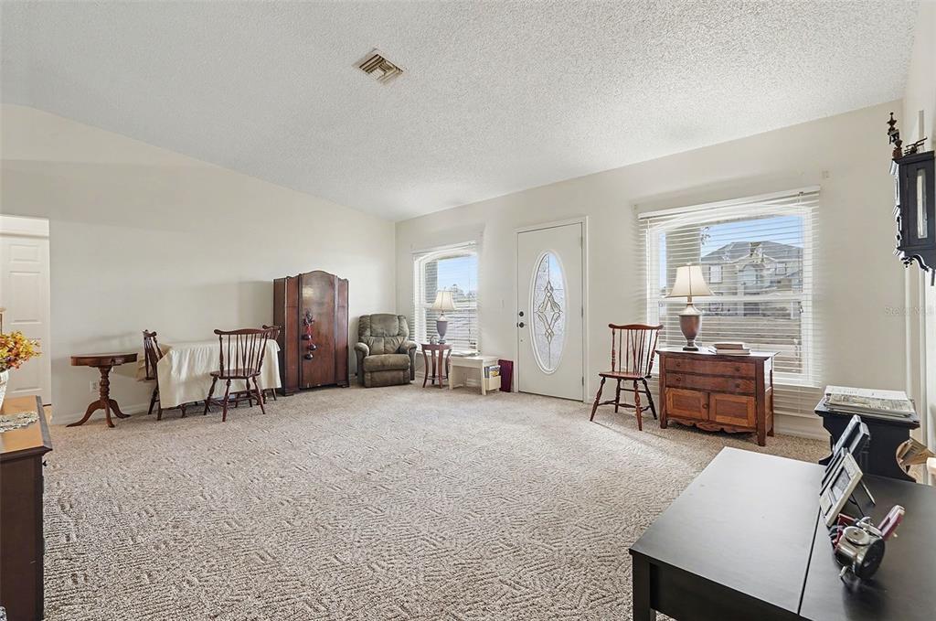 A carpeted living room features a front door, two windows, and various wooden furniture pieces — 598 GANTRY STREET SW, PALM BAY, FL