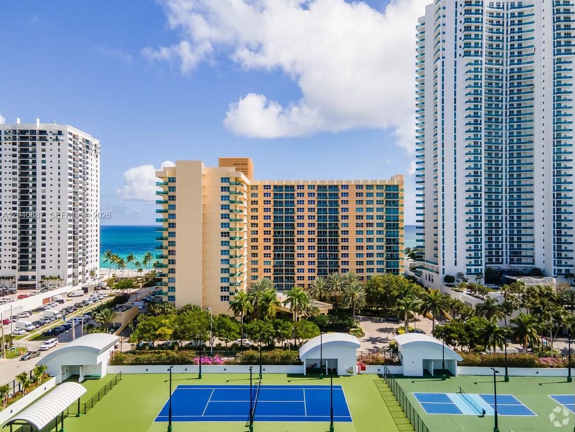An aerial view shows a tennis court in the foreground with high-rise buildings and ocean — 2501 S Ocean Dr # 438, Hollywood FL 33019, HOLLYWOOD, FL