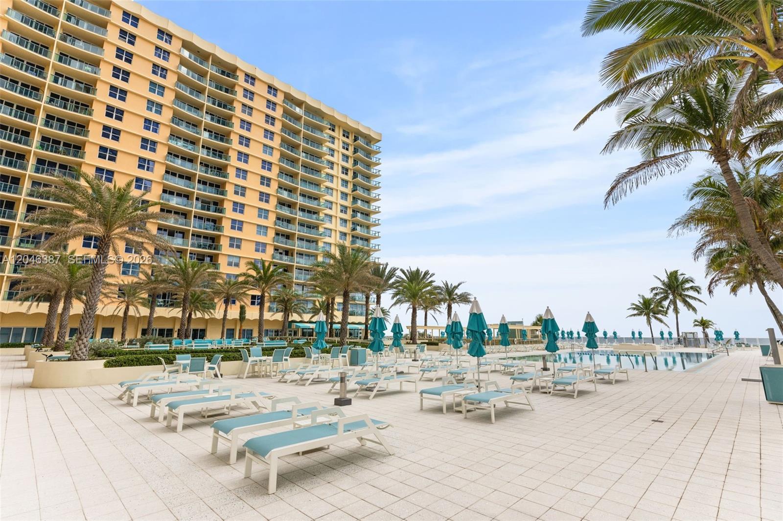 A large multi-story apartment building overlooks a pool deck with lounge chairs and palm trees — 2501 S Ocean Dr # 438, Hollywood FL 33019, HOLLYWOOD, FL