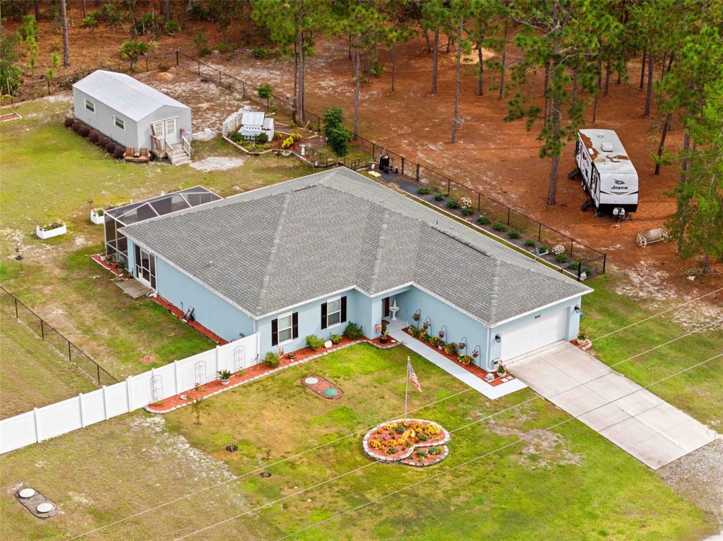 An aerial view shows a light blue house with a gray roof, garage, and yard — 18062 MALIBAR ROAD, WEEKI WACHEE, FL