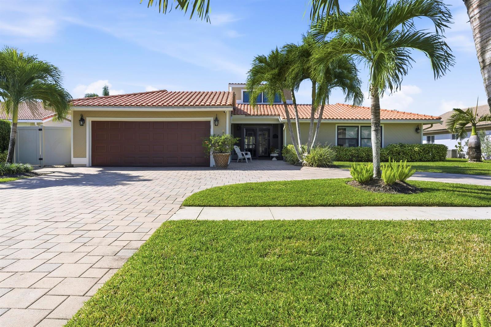 A single-story house with a tile roof, brown garage door, and palm trees in front — 11327 Wingfoot Drive, Boynton Beach FL 33437, BOYNTON BEACH, FL