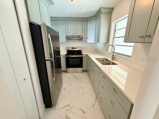 A kitchen features light green cabinets, stainless steel appliances, and white marble-patterned tile flooring — 420 FIREHOUSE COURT UNIT 10, LONGBOAT KEY, FL