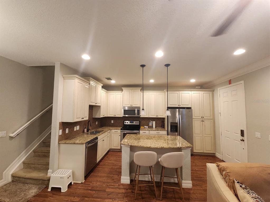 A kitchen with white cabinets, granite countertops, a center island, and wood-look flooring — 10052 EAGLE CREEK CENTER BOULEVARD, ORLANDO, FL