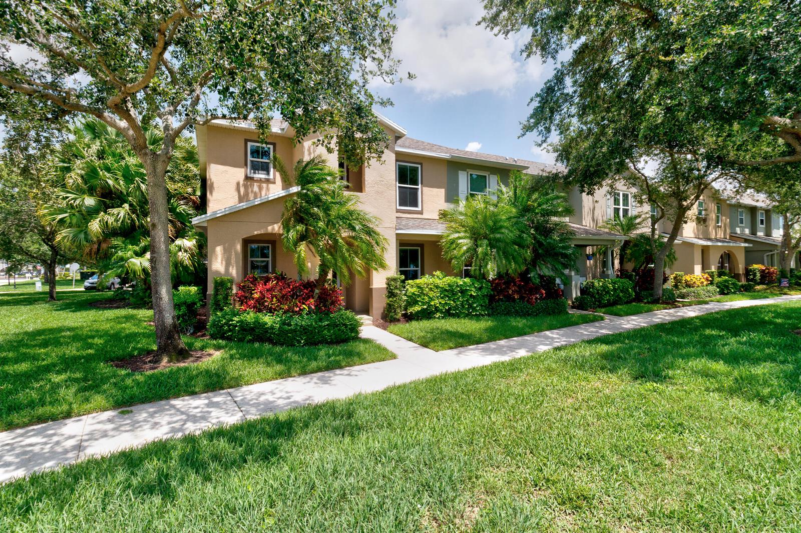 A two-story tan townhouse with a sidewalk and landscaping in front under a blue sky — 1670 Pointe West Way # 1670, Vero Beach FL 32966, VERO BEACH, FL