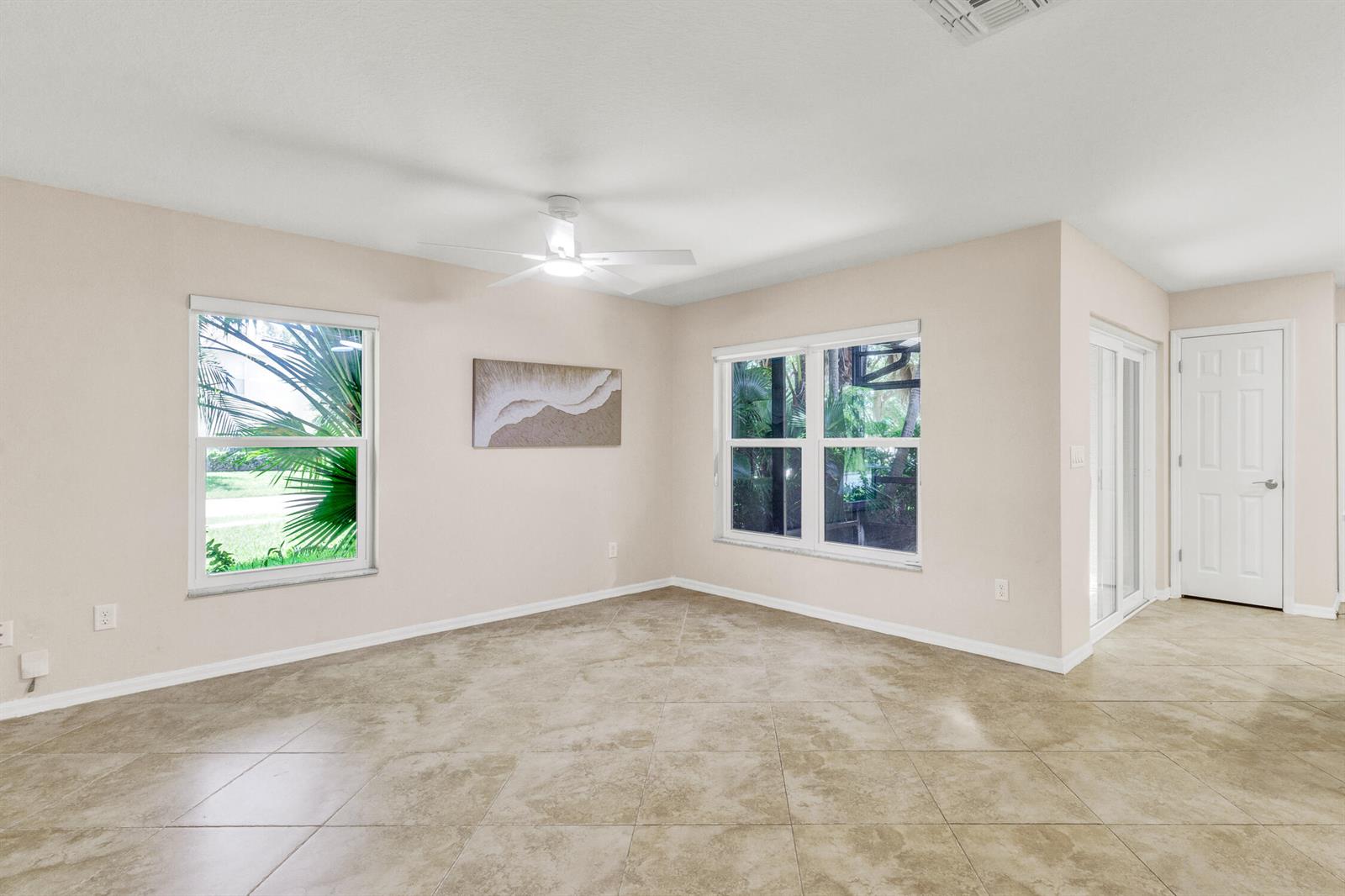 An empty room with beige walls, tile flooring, a ceiling fan, and two windows — 1670 Pointe West Way # 1670, Vero Beach FL 32966, VERO BEACH, FL