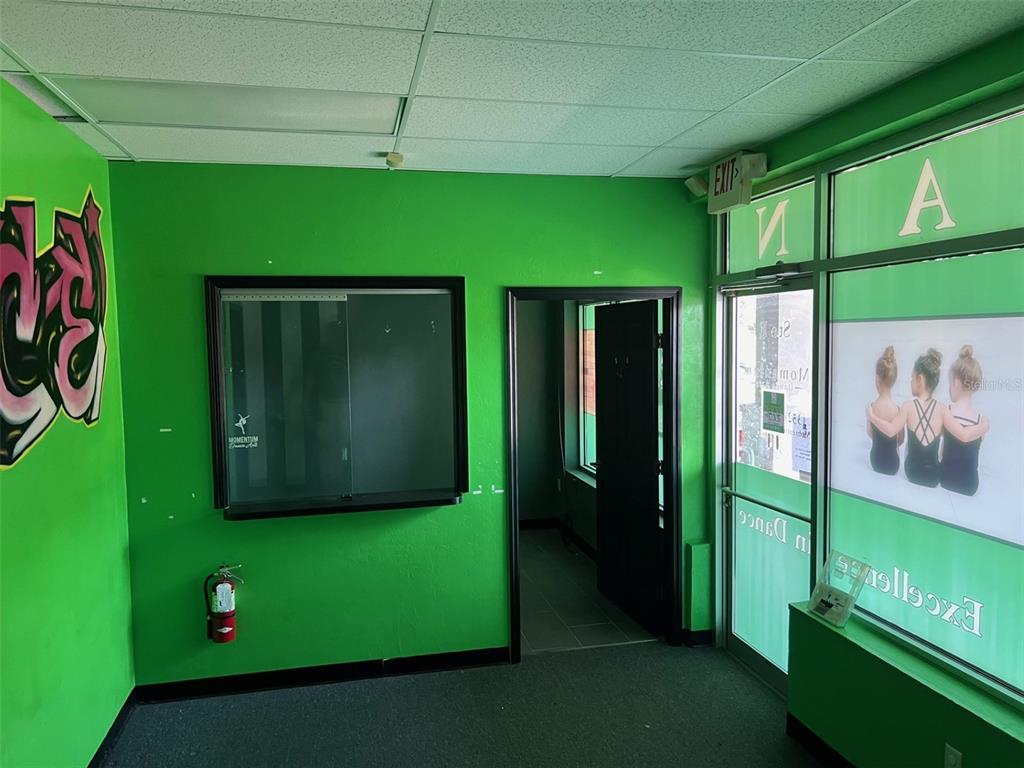 A bright green room features a service window, a doorway, and a glass-fronted entrance — 15634 NW US HIGHWAY 441 UNIT E, ALACHUA, FL