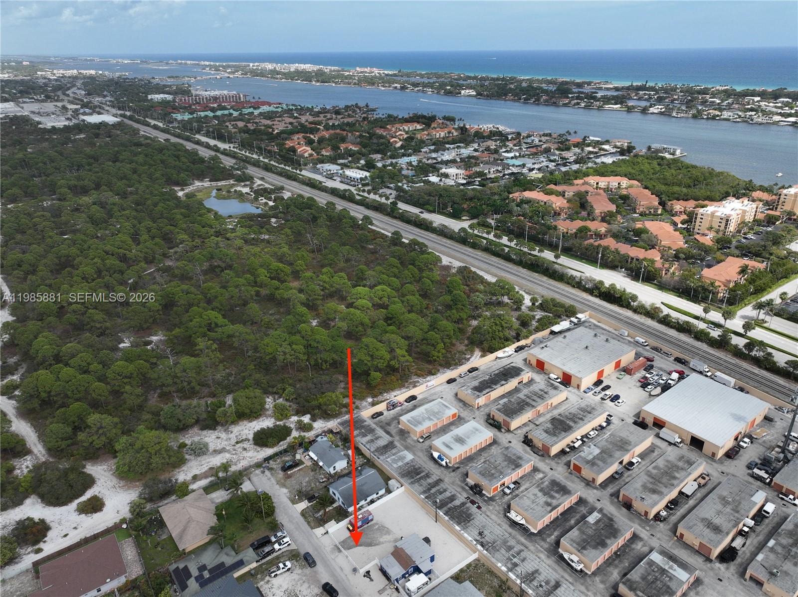 An aerial view shows a small property lot marked with a red arrow near warehouses — 7772 Loomis St, Hypoluxo FL 33462, HYPOLUXO, FL